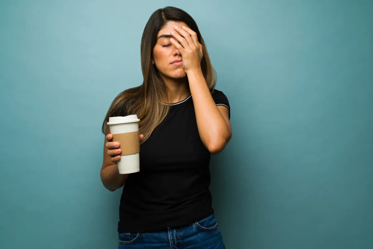 Femme épuisée, une main sur le visage, en pleine journée de travail