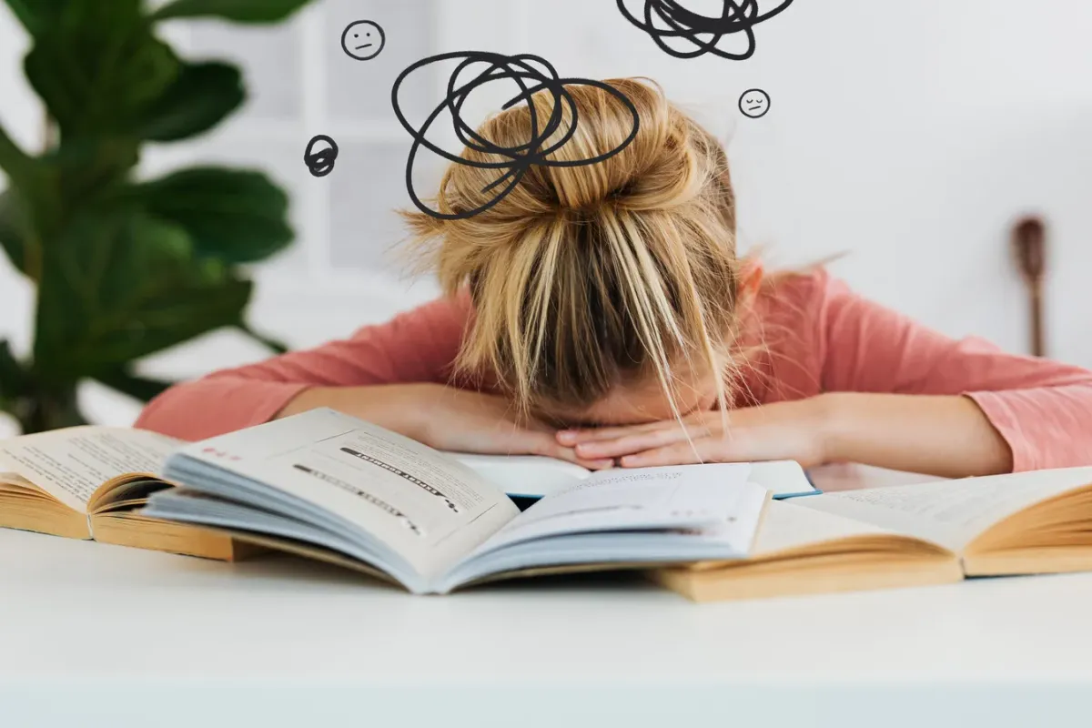 Femme épuisée, la tête posée sur ses livres ouverts, incapable de continuer