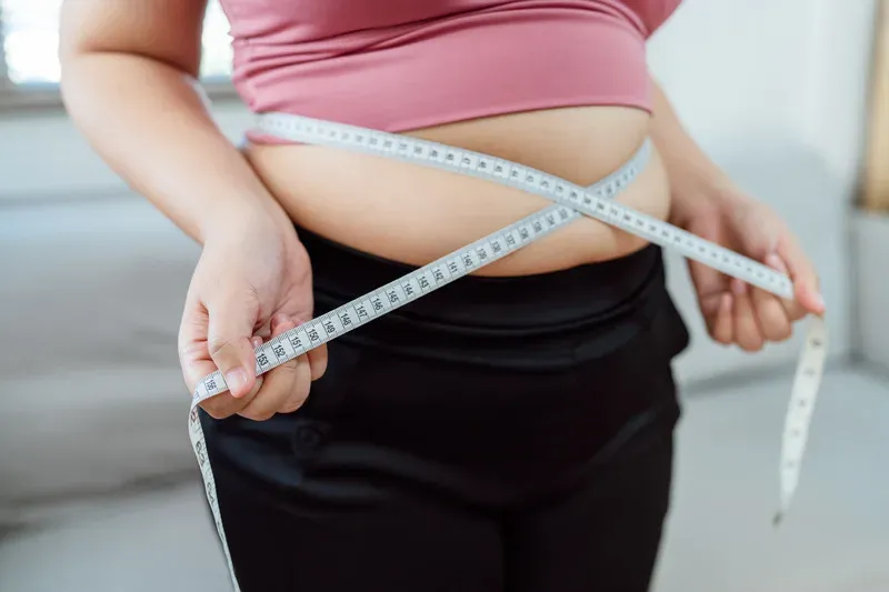 Femme mesurant son tour de taille avec un mètre ruban Femme mesurant son tour de taille avec un mètre ruban