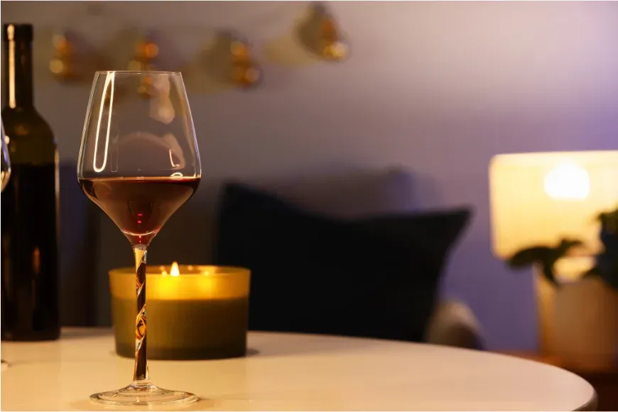 Verre de vin posé sur une table basse près d'une bougie, en soirée