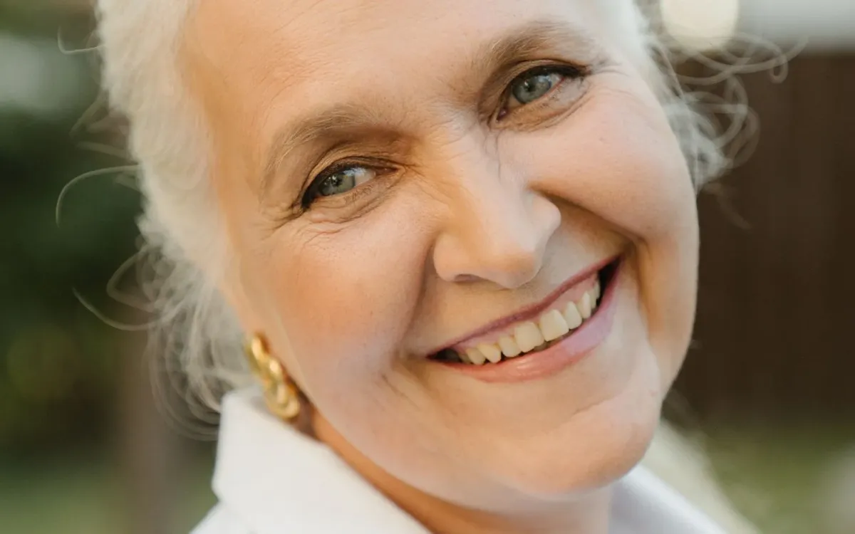 Femme aux cheveux gris, souriante, à l'extérieur