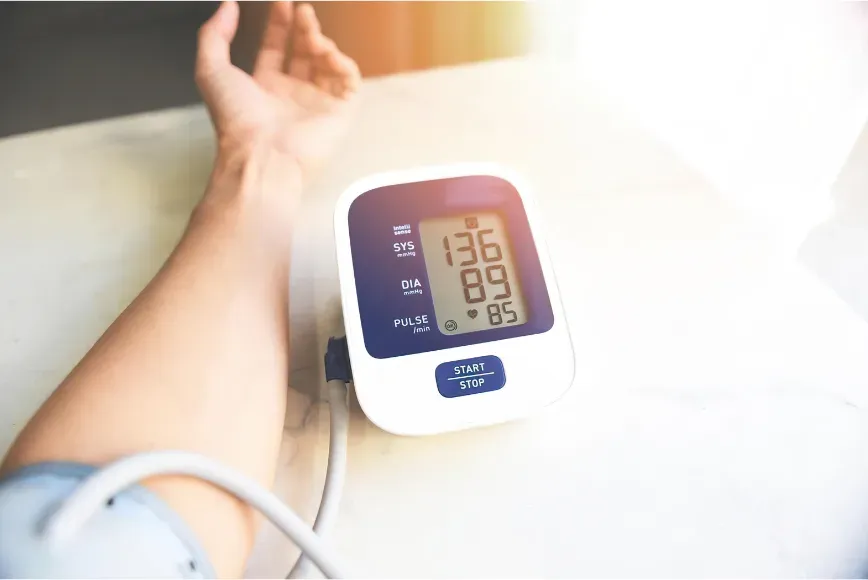 Bras posé sur un lit avec un tensiomètre électronique affichant une mesure