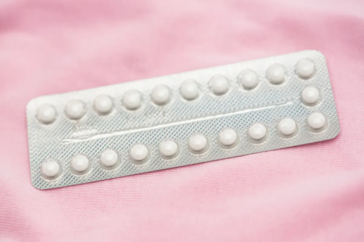 Plaquette de pilule contraceptive posée sur fond rose