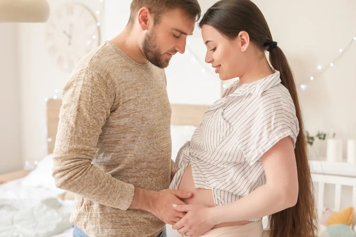Couple enlacé, mains posées sur un ventre arrondi