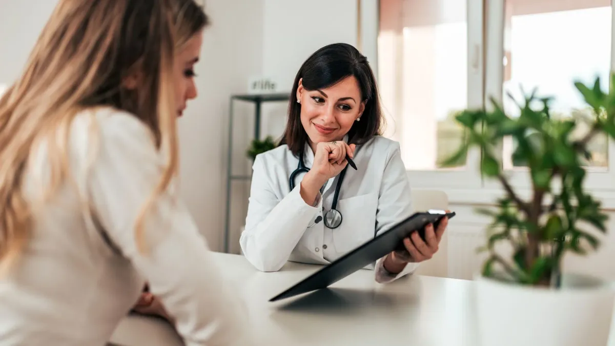 Une patiente et une médecin en consultation, de part et d'autre d'un bureau