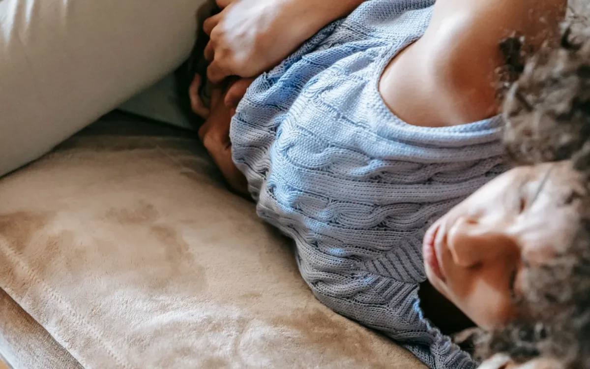 Femme allongée, la main posée sur le bas-ventre