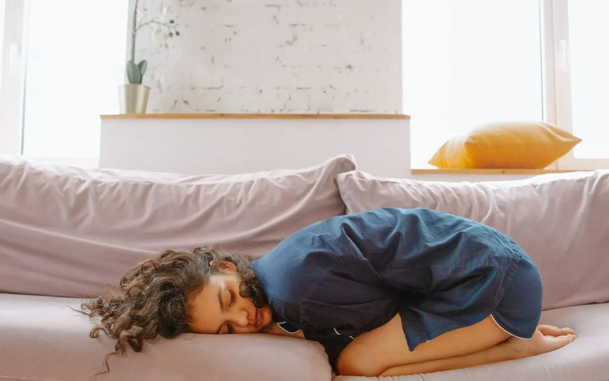 Femme sur un canapé, souffrant de crampes menstruelles