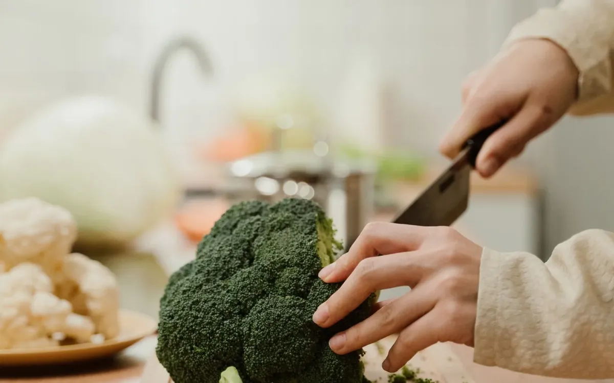 Mains coupant du brocoli bio sur un plan de travail