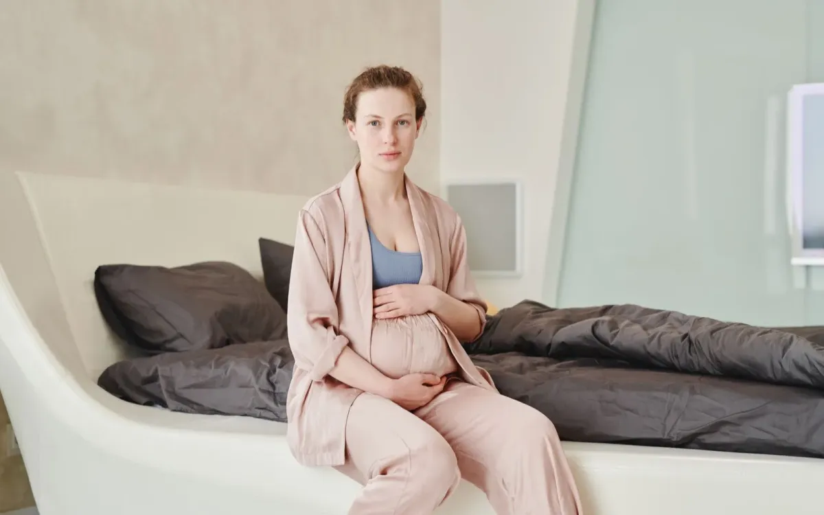 Femme assise au bord de son lit dans la lumière du matin