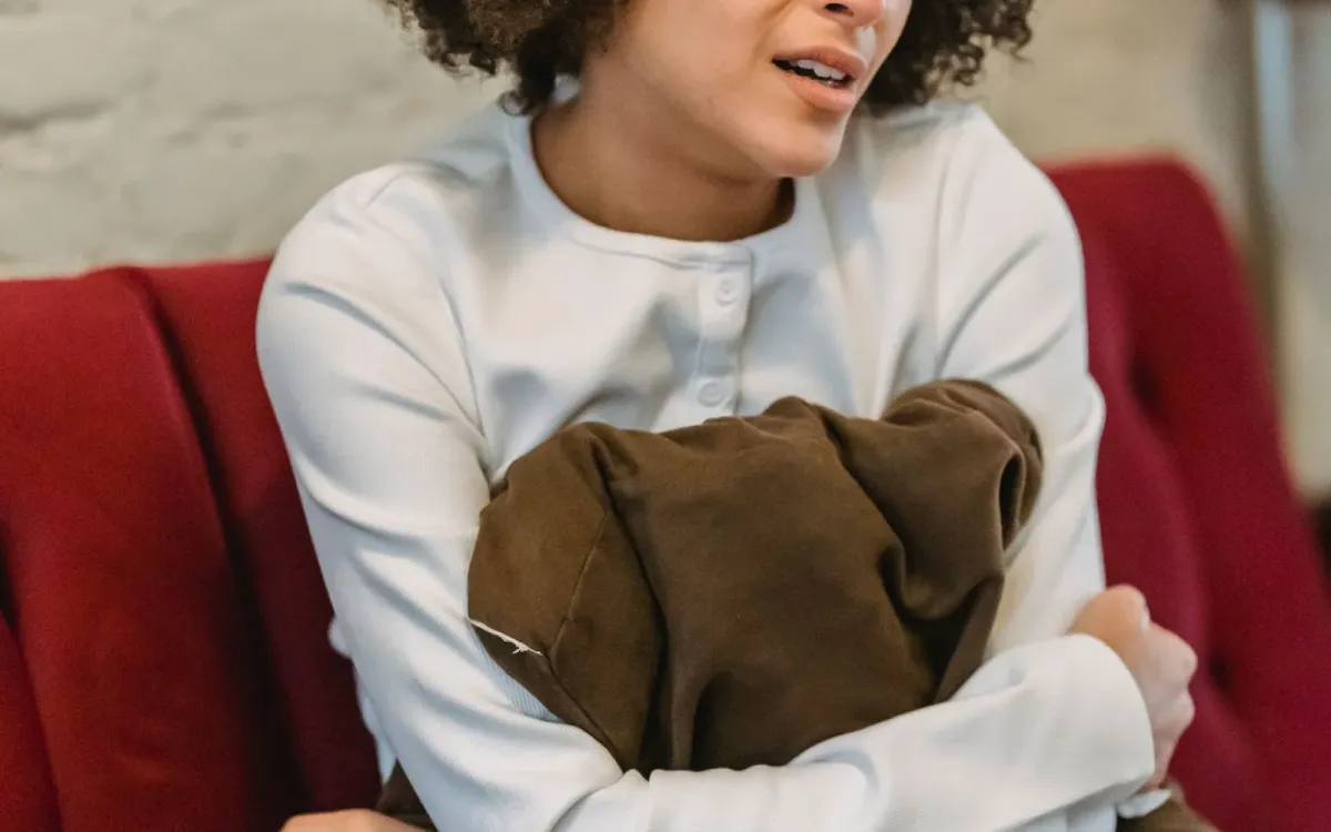 Femme allongée sur un canapé, un coussin serré contre elle
