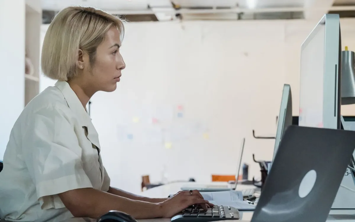Femme concentrée devant son ordinateur en fin de journée, épaules tendues