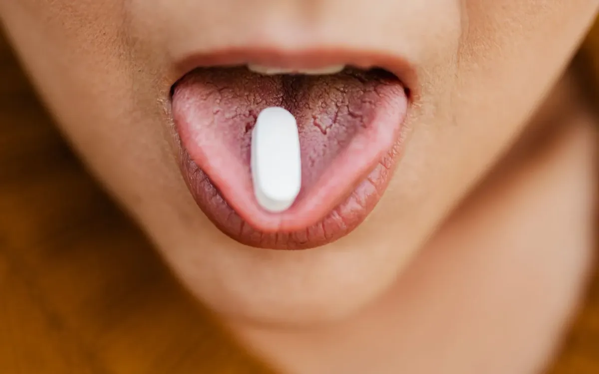 Comprimé blanc posé sur la langue, la prise du matin