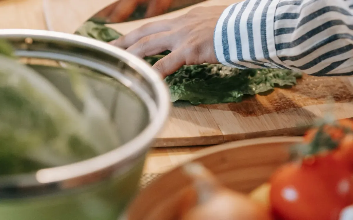 Mains qui tranchent des légumes sur une planche en bois