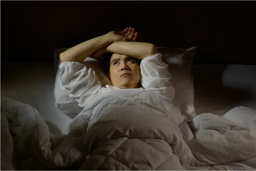 Femme éveillée dans son lit la nuit, les yeux ouverts