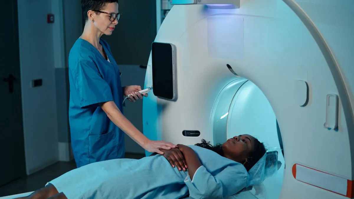 Manipulatrice en radiologie installant une patiente devant un appareil d'IRM