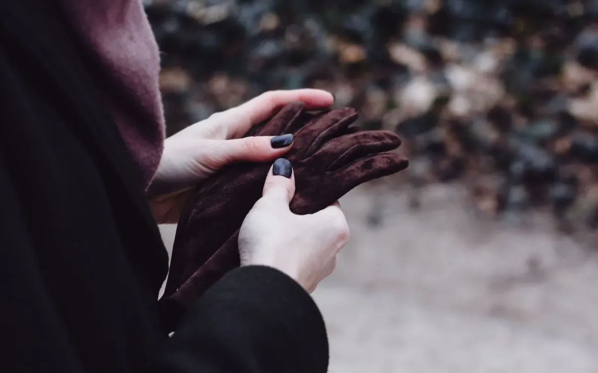 Mains nues d'une femme tenant ses gants à l'extérieur par temps froid
