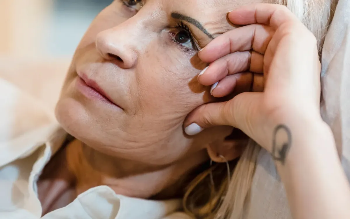 Femme d'une cinquantaine d'années, pensive, la main sur le visage