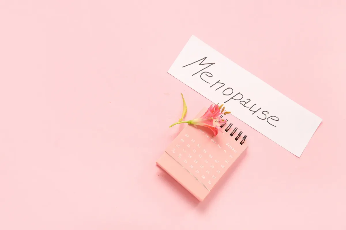 Calendrier de bureau posé sur fond rose portant l'inscription Ménopause