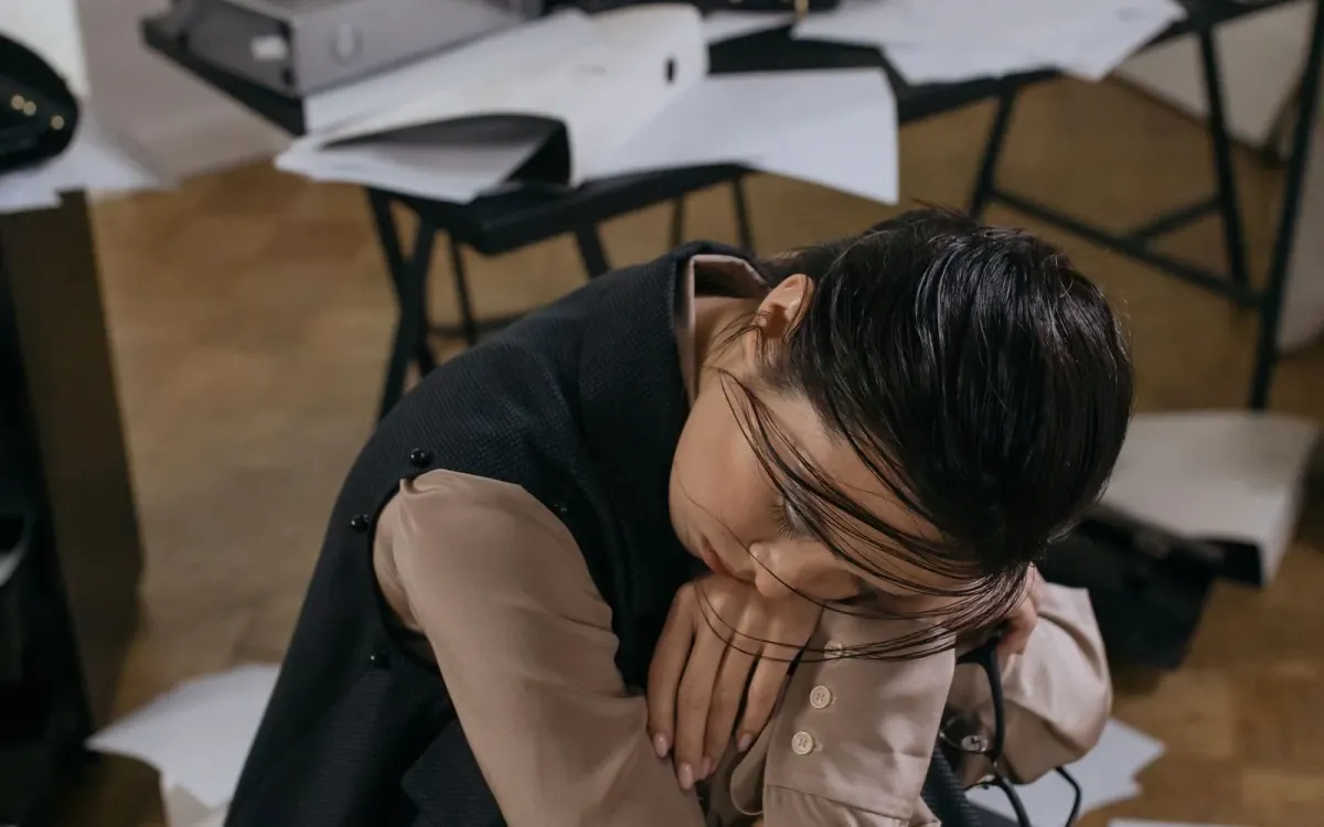 Femme au bureau, épuisée, la tête appuyée sur la main