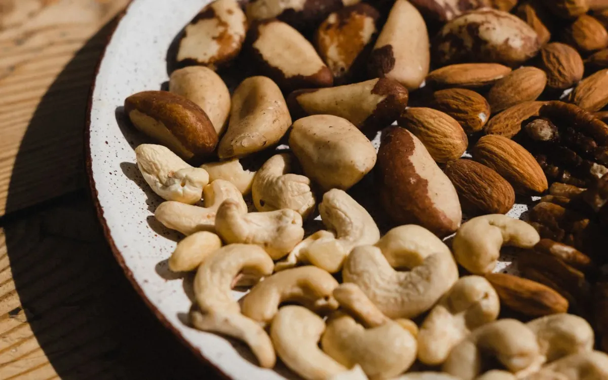 Noix du Brésil décortiquées mêlées à des noix de cajou et des amandes dans une assiette Noix du Brésil décortiquées mêlées à des noix de cajou et des amandes dans une assiette