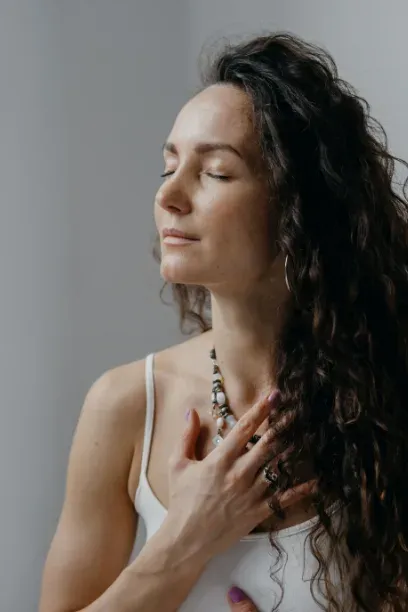 Femme aux cheveux bouclés, yeux fermés, la main posée sur la poitrine