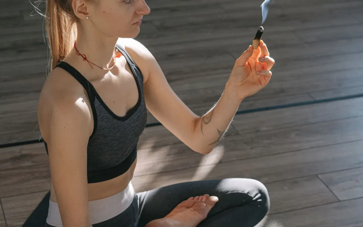 Femme en méditation, un bâton de palo santo allumé