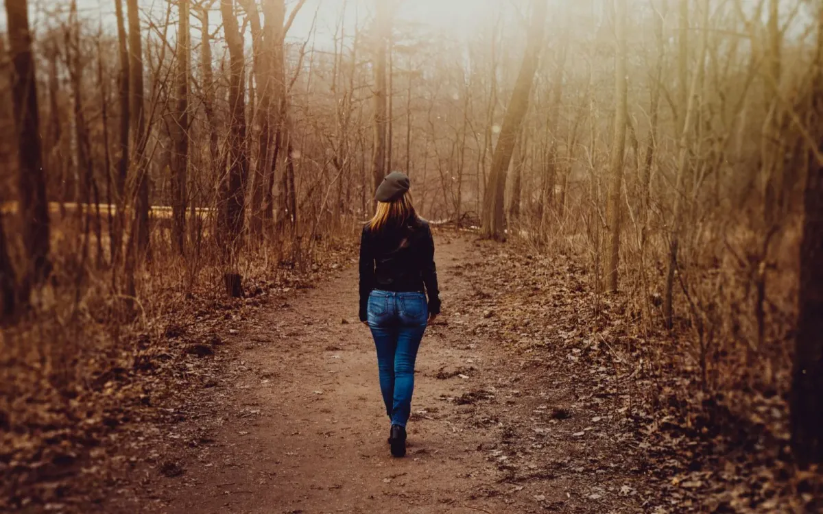 Femme qui marche sur un sentier brumeux en automne