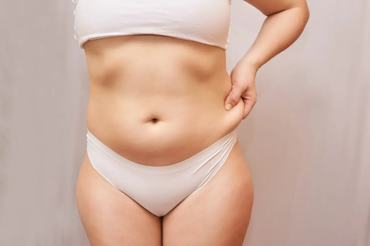 Femme debout pinçant la peau de son ventre au-dessus de la taille