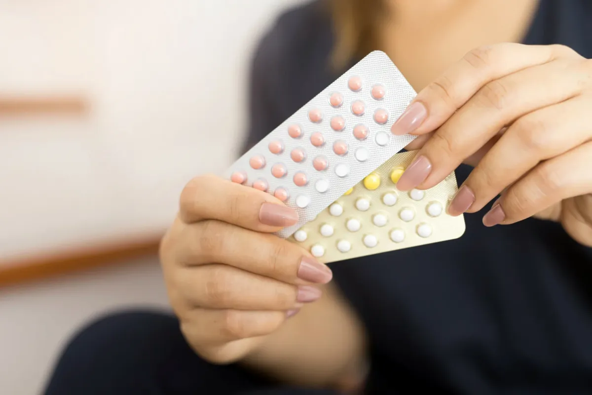 Femme tenant deux plaquettes de pilule contraceptive, au moment de décider de l'arrêt