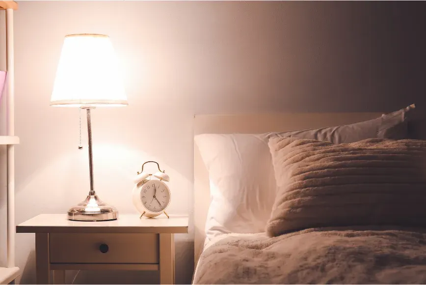 Lampe de chevet allumée dans une chambre douce, le soir