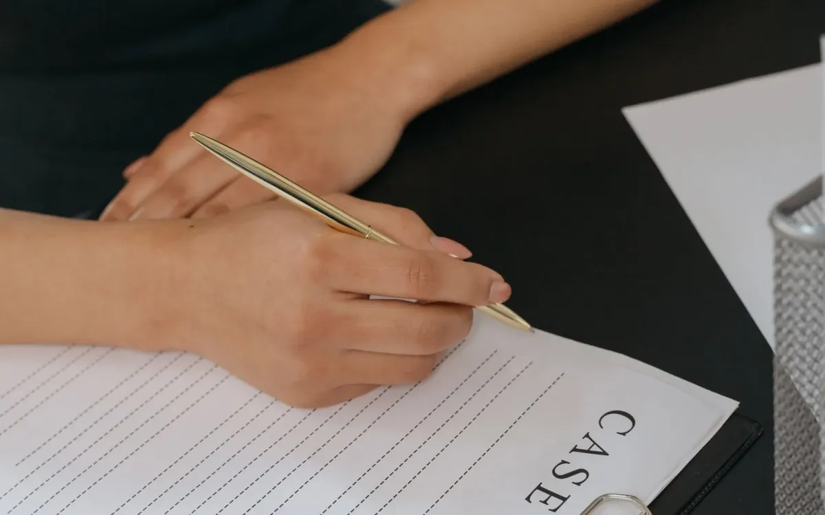 Main d'une femme remplissant un formulaire au stylo