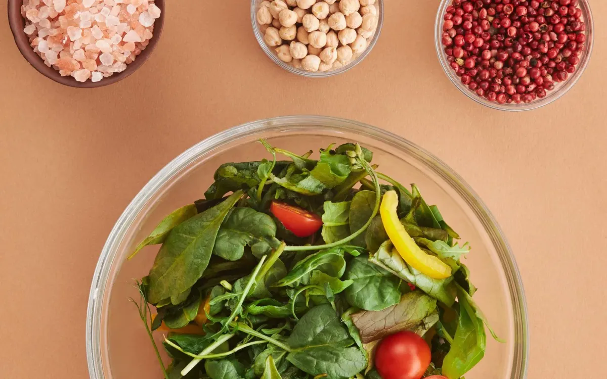 Saladier de crudités entouré de graines et de légumineuses