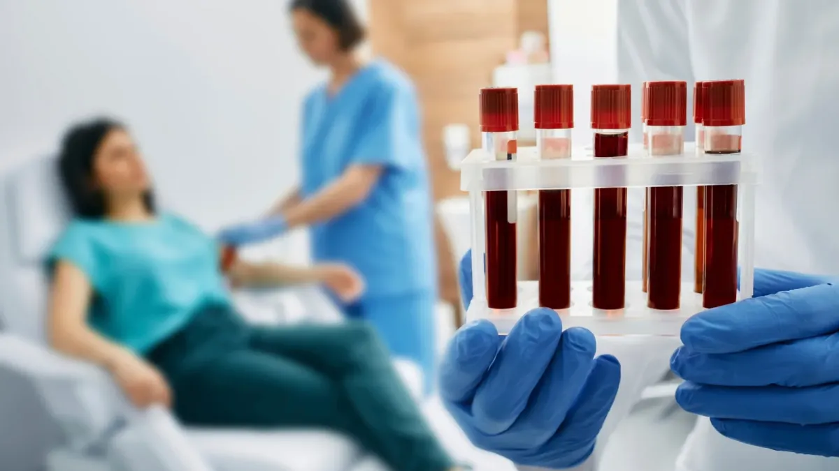 Tubes de prélèvement sanguin tenus par une soignante gantée