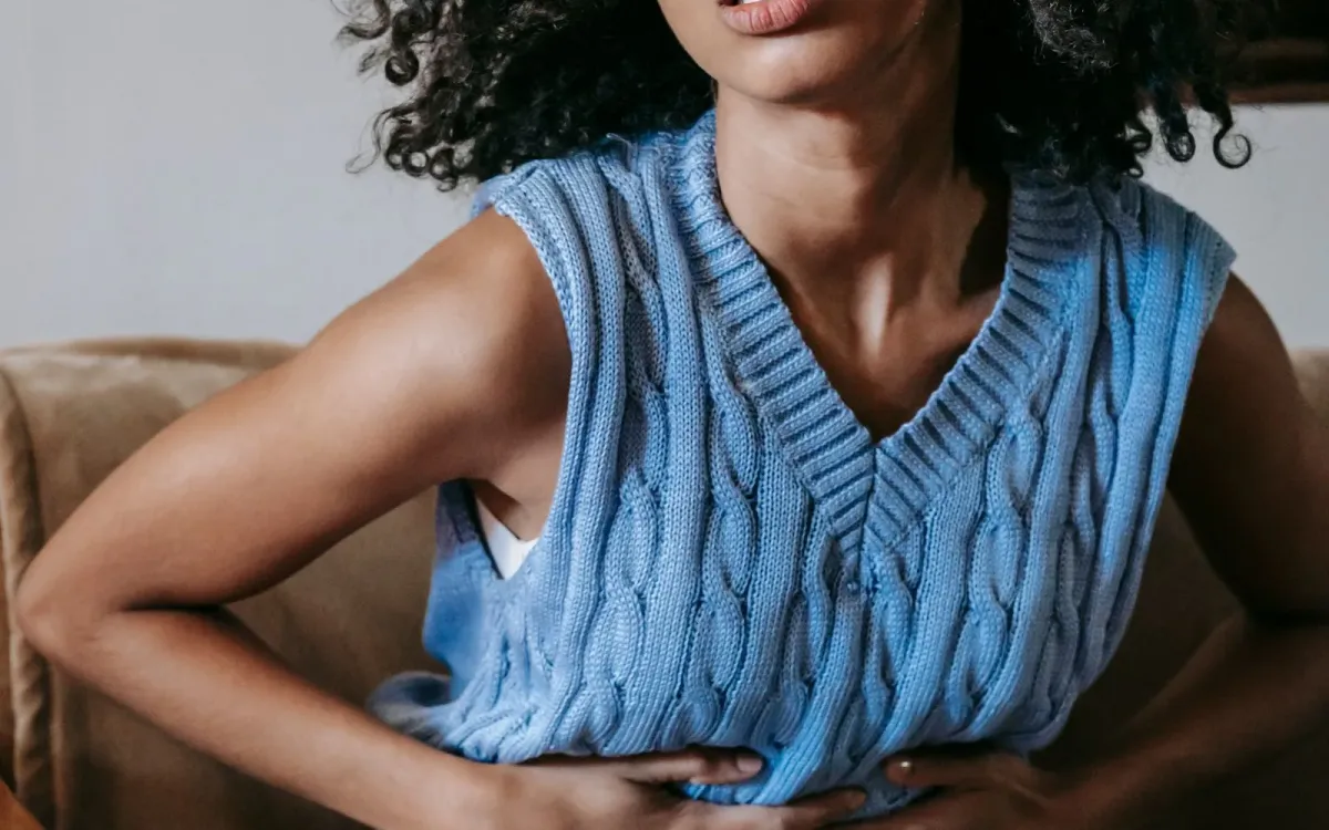Femme debout, les mains serrées sur le bas-ventre