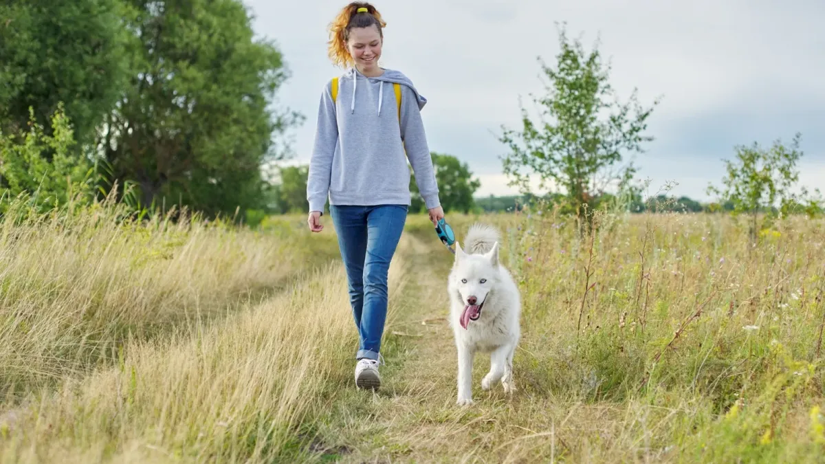 Femme marchant sur un chemin de campagne avec son chien
