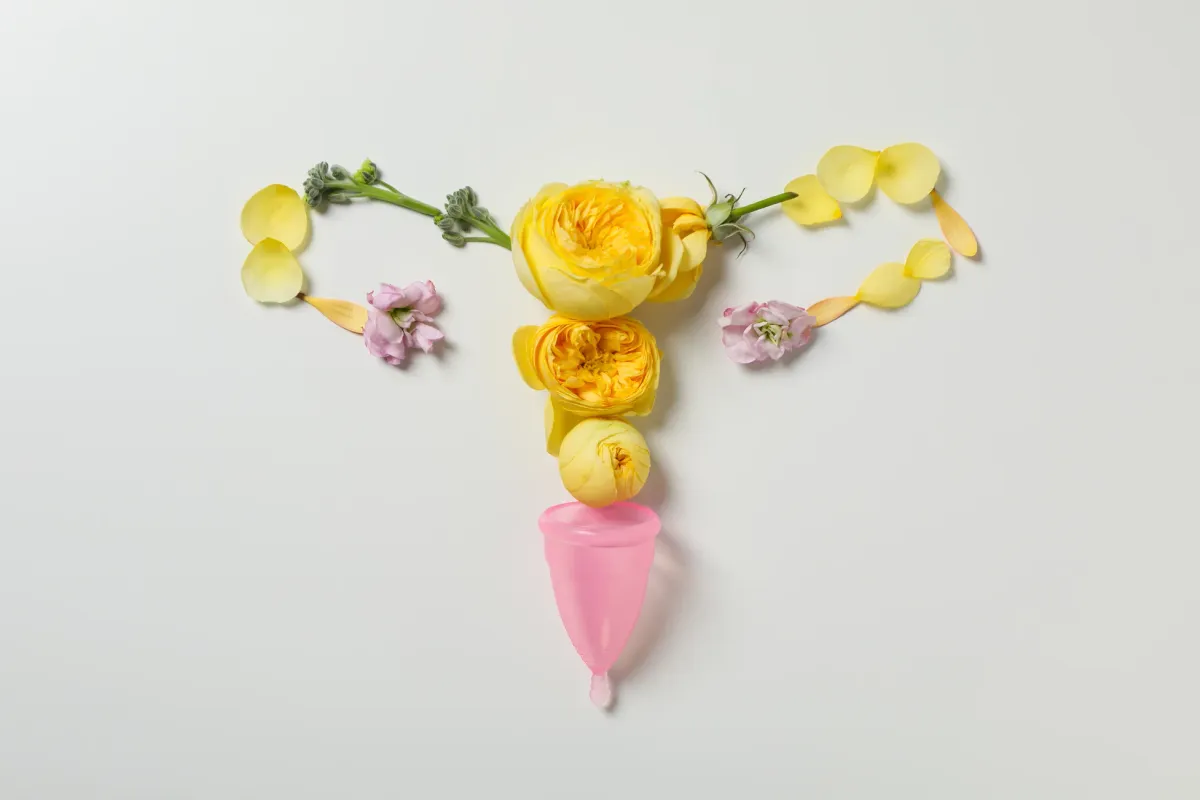 Utérus composé de fleurs jaunes à côté d'une coupe menstruelle