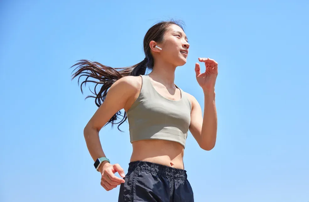 Femme en tenue de sport courant sous un ciel bleu