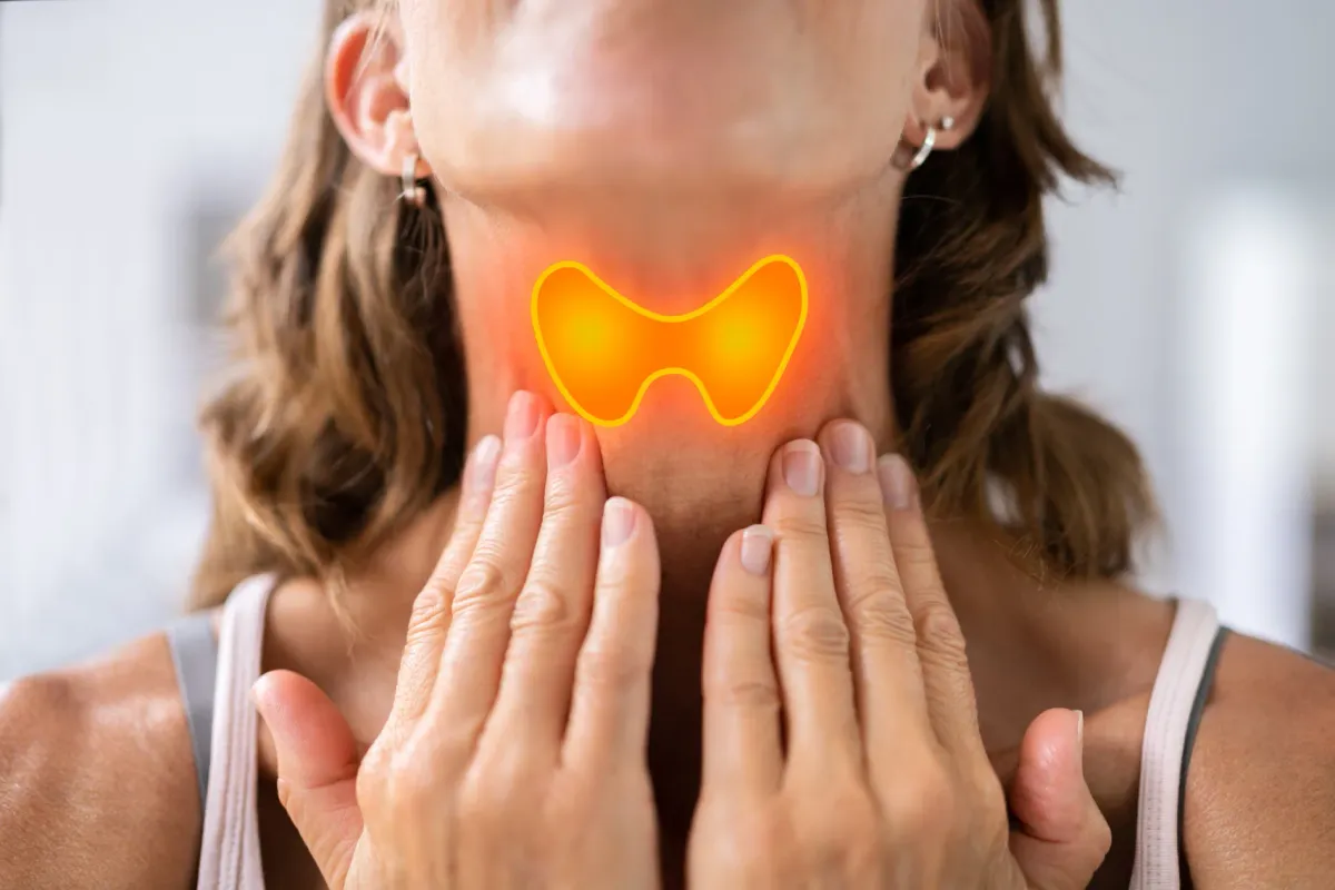 Femme posant ses deux mains sur sa gorge, thyroïde mise en évidence