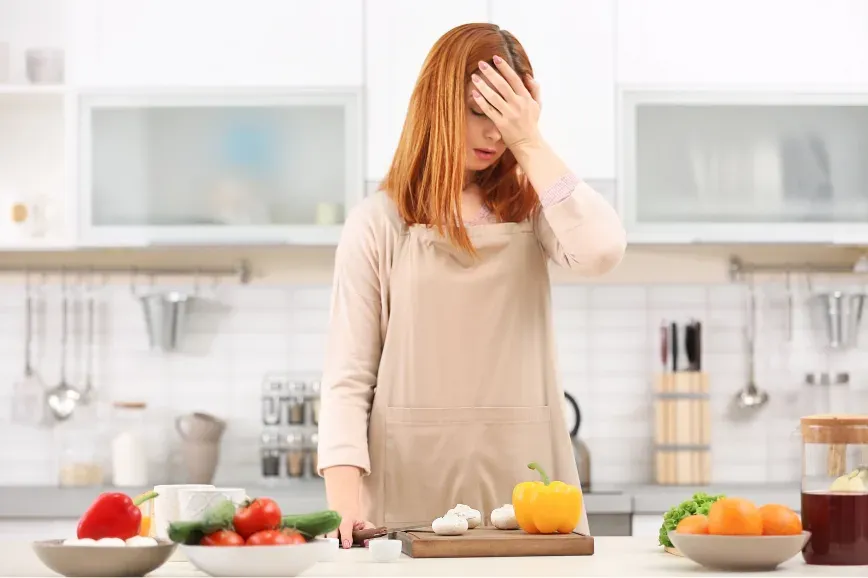 Femme fatiguée dans sa cuisine le matin, la main sur le front