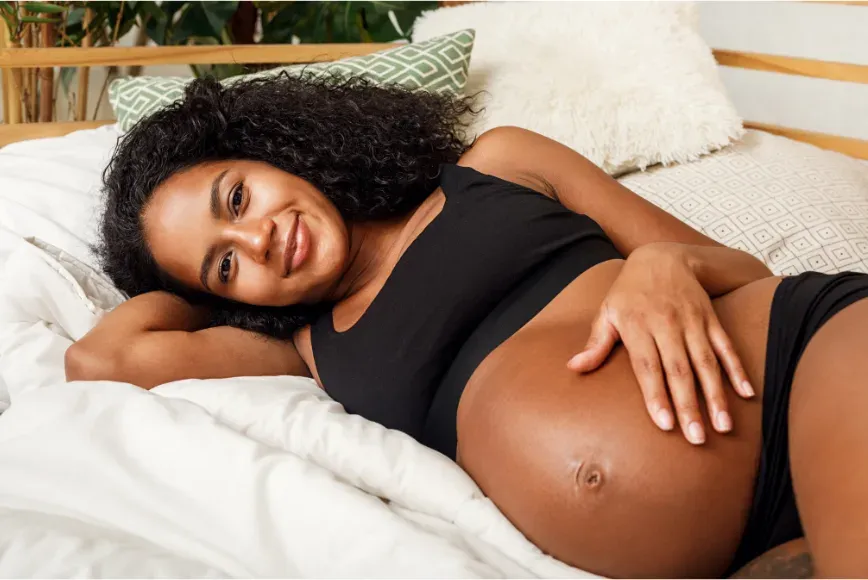 Femme enceinte allongée sur le côté, une main sur son ventre