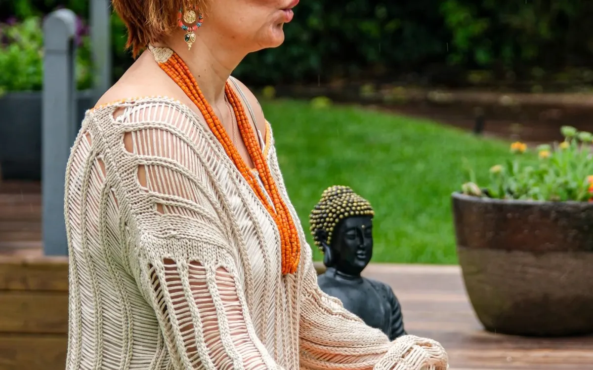 Femme assise en méditation sur un tapis, dans un jardin
