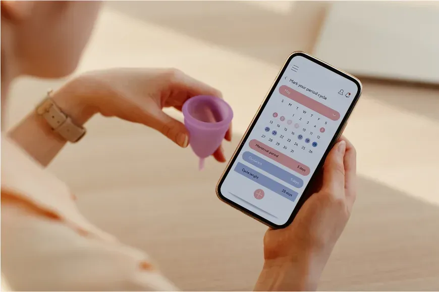 Mains tenant un téléphone affichant une application de suivi du cycle