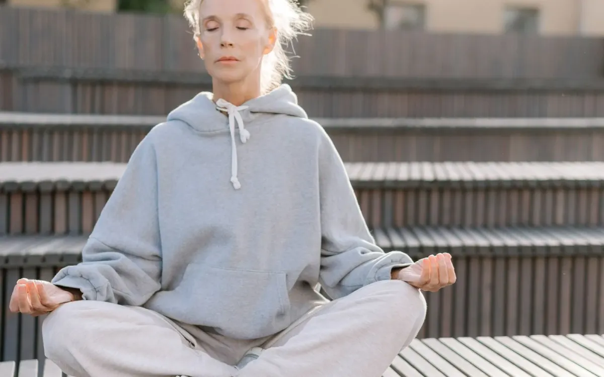 Femme d'une cinquantaine d'années en méditation à l'extérieur