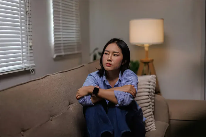 Femme assise seule le soir près d'une lampe, l'air préoccupée