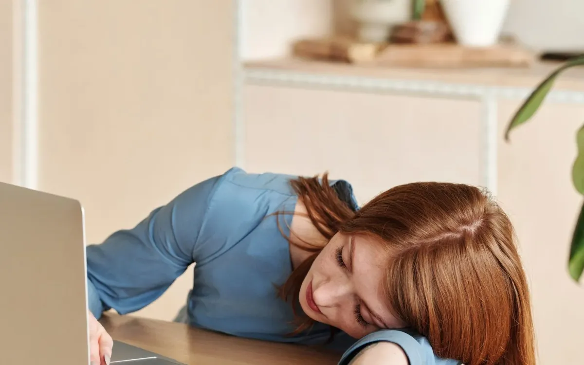 Femme endormie sur son bureau, épuisée en pleine journée