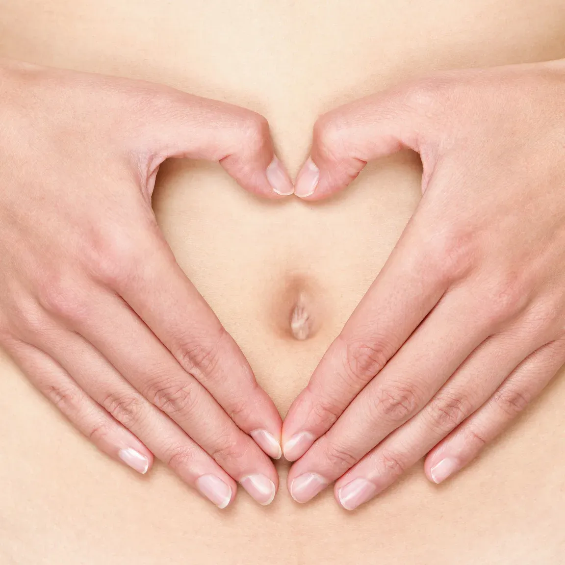 Mains formant un cœur sur le bas-ventre, symbole de l'apaisement du syndrome prémenstruel