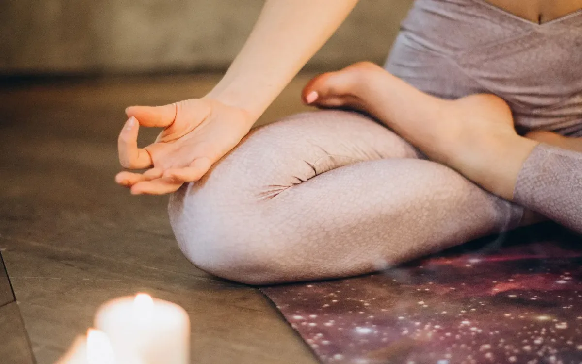 Femme assise en lotus près de bougies allumées