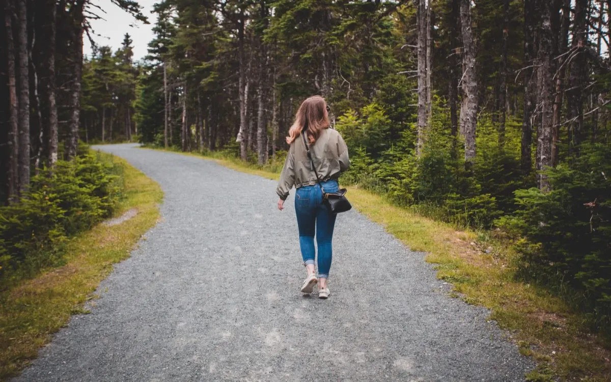 Femme qui marche sur un chemin forestier en été