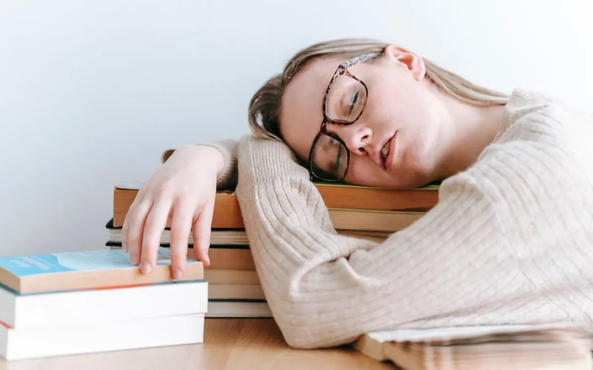 Jeune femme endormie de fatigue, la tête posée sur ses bras croisés