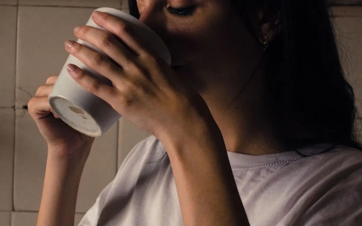 Femme emmitouflée dans une couverture, une boisson chaude à la main